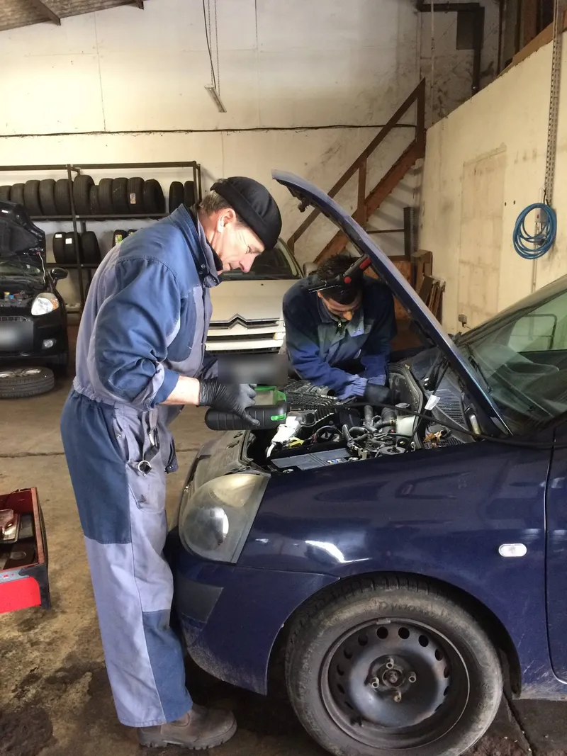 Mécaniciens d'AP Auto vérifiant le compartiment moteur d'une voiture